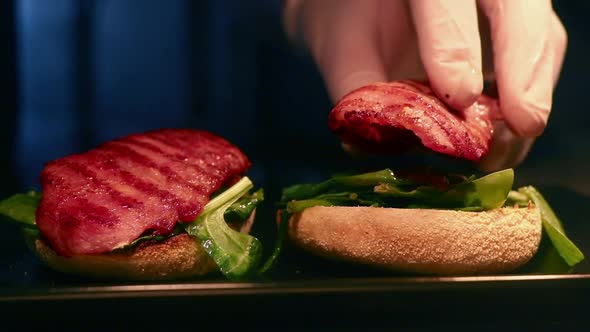 Tasty Burgers prepared with Delicious Bacon and Leafy Greens in Slow Motion