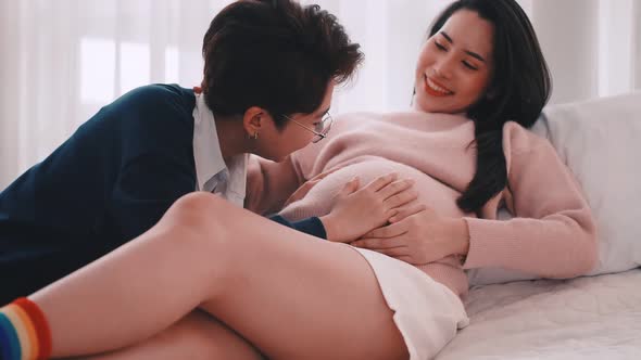 Pregnant Asian lesbian woman and her partner are happy to spend time together at home.