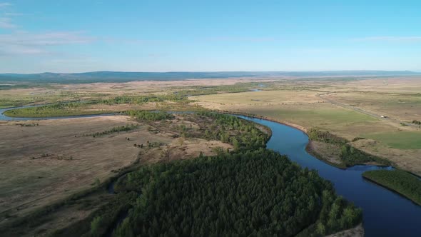 Aerial View of a River Flowing Through Rural Area with Meadows Rare Trees and with the Road on the