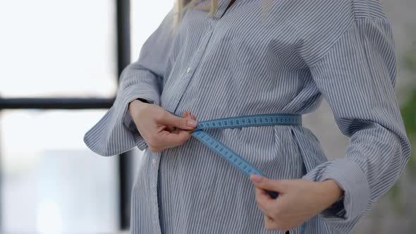 Unrecognizable Woman Measuring Pregnant Belly in Bedroom in the Morning