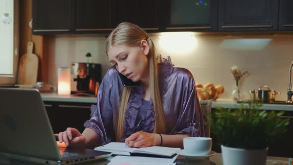 Young Business Woman Working at Home By Sitting at the Computer and Speaking By Smartphone