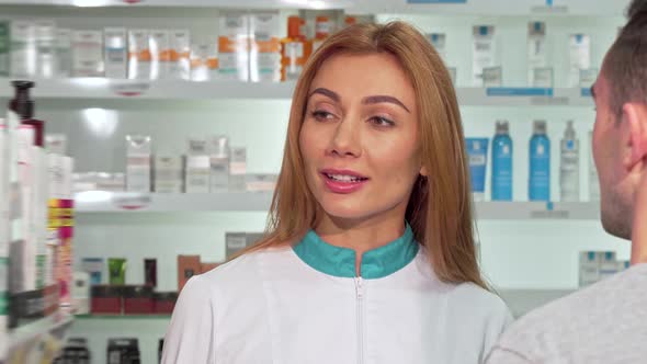 Friendly Female Pharmacist Helping a Customer at the Drugstore