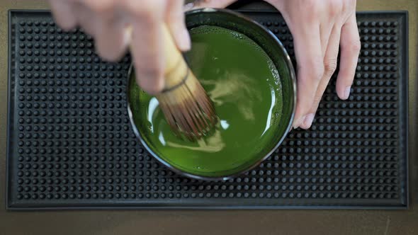 4K Asian woman barista making iced matcha green tea latte serving to customer at cafe