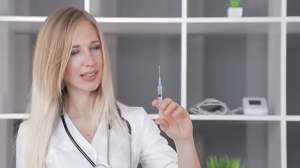 Doctor a Woman of Good Appearance Holds a Syringe in Her Hand and Releases Excess Air From the