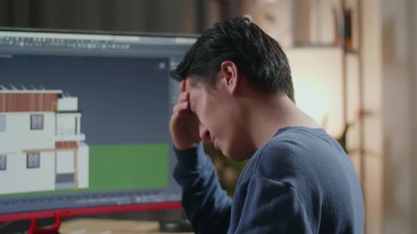 Close Up Of Asian Male Engineer Having A Headache While Designing House On A Desktop At Home