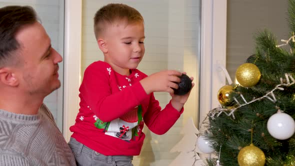 Cute Son Decorating the Christmas Tree with His Father in the Living Room