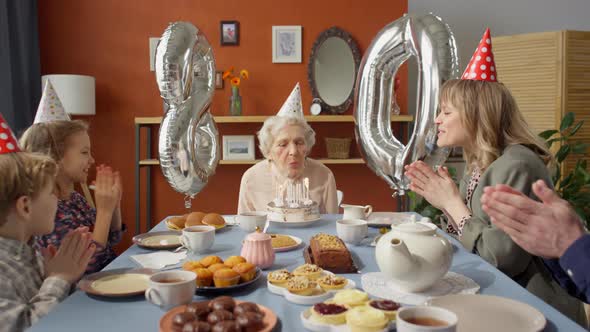 Grandmother Blowing Candles on Birthday Cake at Family Celebration