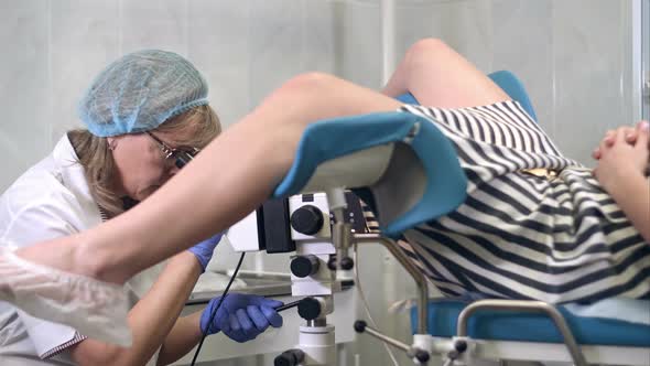 Woman Gynecologist Examining Female Patient Using Colposcope