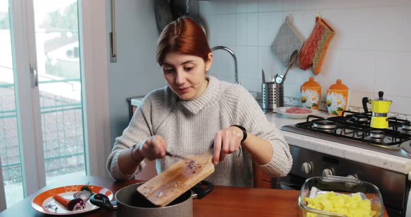 Girl is Pouring Onions Into the Fry Pan for Homemade Dinner