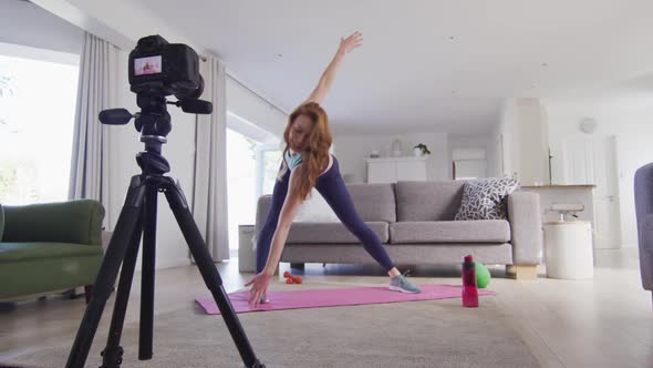 Woman performing exercise at home and recording it with digital camera