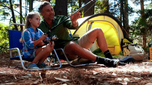 Father teaching son to use fishing rod in the park