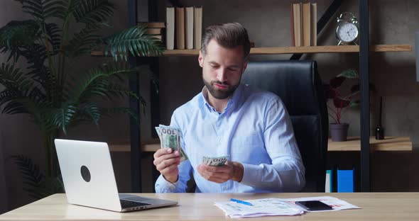 Young Male Entrepreneur Counting Money at His Desk