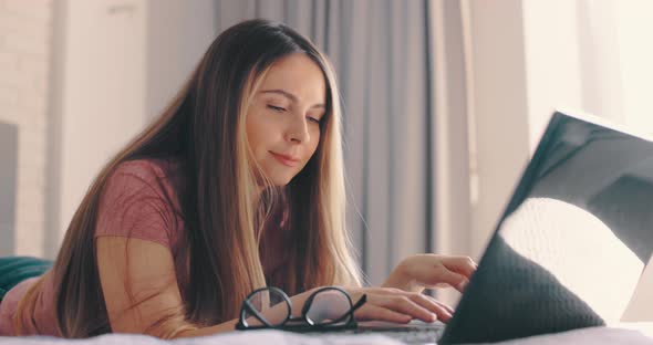 Woman Typing on Laptop on Bed at Bedroom