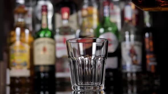 Closeup of a Bartender Pouring Cognac Into a Glass for a Businessman in a Bar