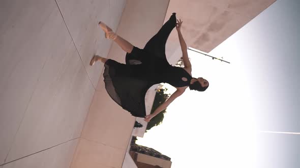 Young Professional Ballerina in Black Dress Is Dancing Outdoors