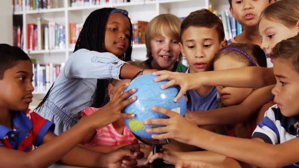 School kids studying globe in library