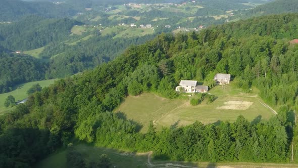 Countryside highlands green summer forest and meadows with farm houses. Aerial 4k view.