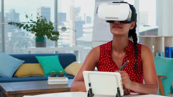 Female graphic designer in virtual reality headset using digital tablet at desk 4k