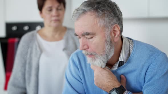 Rack Focus From Stressed Sad Senior Man to Loving Middle Aged Woman Hugging Husband and Talking