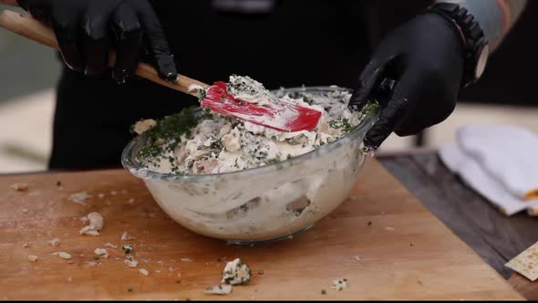 Man mixes chopped fish ingredients chives in a bowl at the smoker. Concept: BBQ, Smoker, outside gri