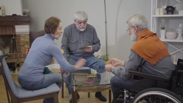 Portrait of Senior Caucasian Man Playing Cards with Friends in Nursing Home. Retirees Enjoying