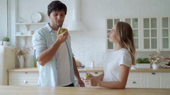 Young Couple with Food at Home Kitchen Together. Close Up of Smiling Man Eating Apple with Woman.