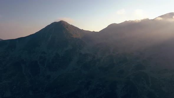 Wide aerial drone slowly tilting up from camping site on top of mountains. Shot ends with full horiz