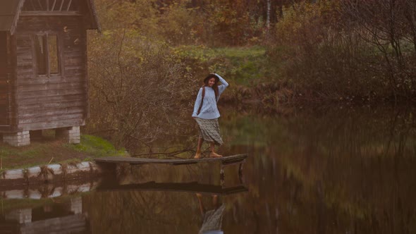 Old Wooden House Hut By Lake Among Autumn Forest Woman Walking By Wooden Pier