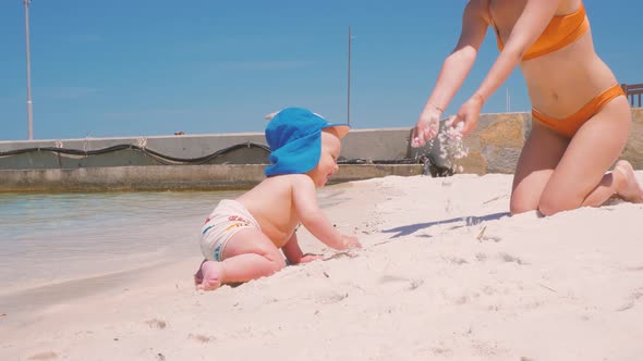 For the First Time, a Child Near the Ocean with His Mother Touches Salt Water 