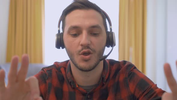 Attractive Man, Freelancer Wearing Headphones and Talking During a Work Video Conference Call From