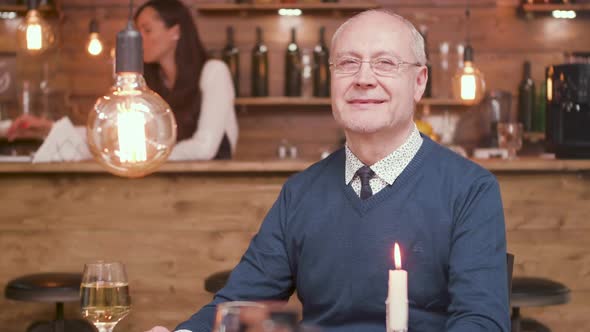 Portrait of a Handsome Old Man Smiling at the Camera in a Bar