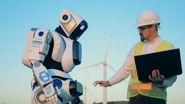 Male Specialist Is Regulating Robot's Settings on Its Touchpad