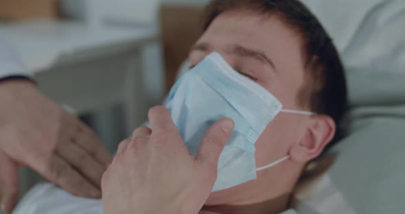 Portrait of Ill Man in Medical Mask Choking From Coughing on Bed