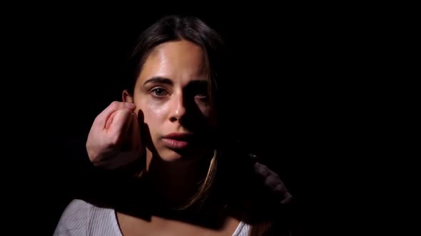 Scared Girl Against the Background of Husband Standing Behind Her with a Fist