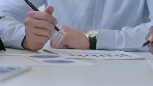 Close Up of Hands of Three Business People Writing on Paper While Talking