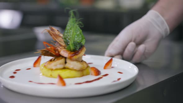 Male Hand Pushing Plate with Fried Tasty Prawns on Pineapple Indoors