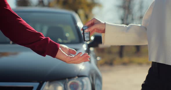 Famale Hand Gives a Car Keys to Male Hand in the Car Dealership Close Up