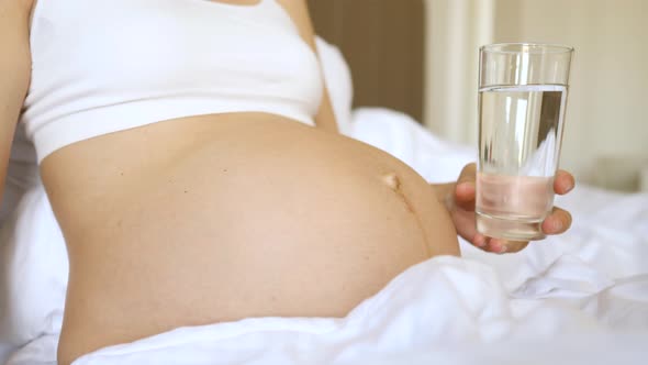 Closeup Of Pregnant Woman Holding Glass Of Water