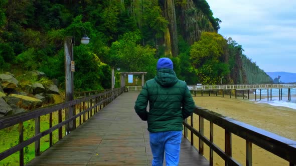 Man Walking to Lava Pillars on Wooden Pier