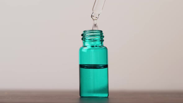 serum is pipetted in glass bottle and dripped into bottle. White background.