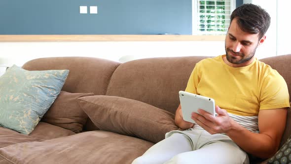 Smiling couple using digital tablet on sofa in the living room