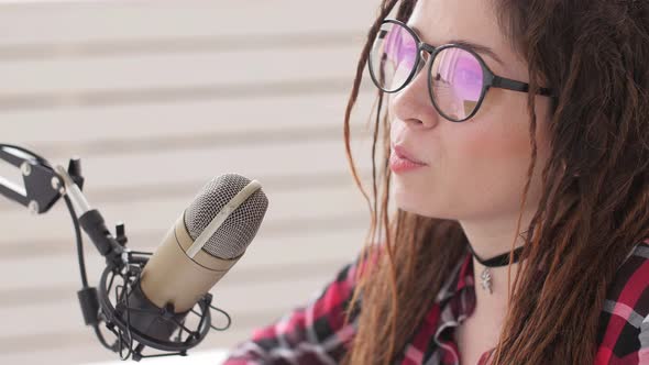 Concept of Streaming and Broadcasting. Young Cheerful Girl in the Studio Speaks Into a Microphone