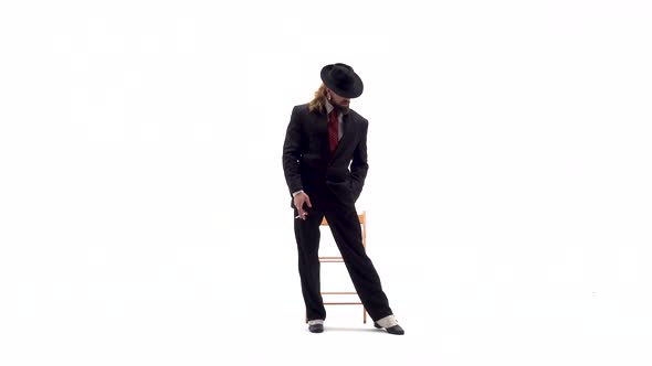 Elegant Man in a Black Hat Is Dancing an Erotic Dance, He Uses a Chair and a Cigarette