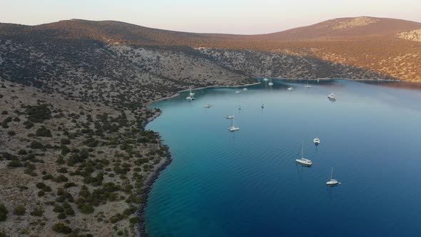 Catamaran and Sail Yachts Anchored at Bay on Deep Blue Sea Water on Sunrise