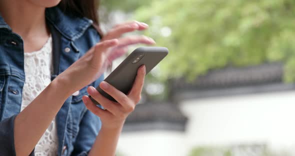 Woman use of mobile phone in chinese garden