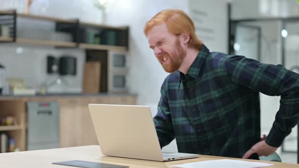 Beard Redhead Man with Back Pain Using Laptop in Cafe