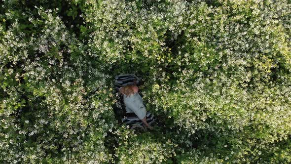 Aerial Spin of Young Woman Lying in Flowers