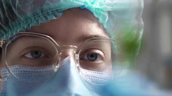 Close Up Of A Girl's Eyes Eyeglasses Of A Girl Doctor Laboratory Assistant Looks At Glass Test Tube