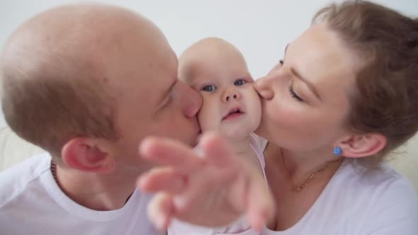 Happy Family Concept. Parents Kissing Baby Smiling.