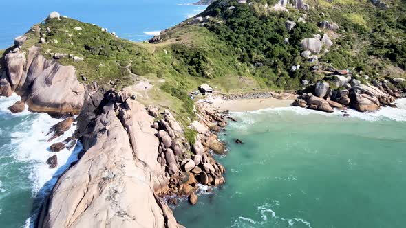Aerial drone view of deserted beach with many rocks and rocks hidden among mountains in tropical bea